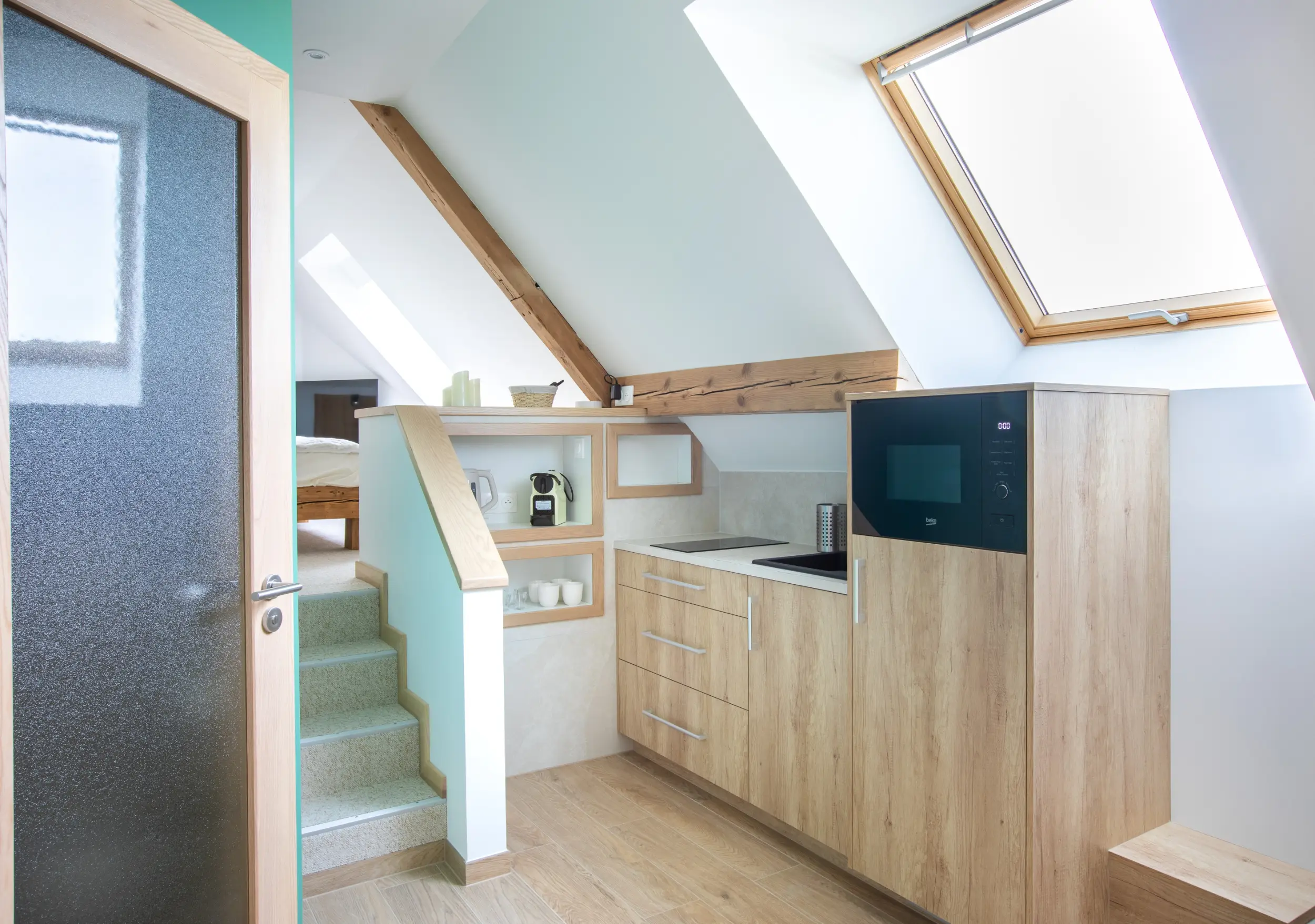 Coin cuisine du gîte Porte D, lumineux et équipé avec plaques, micro-ondes, rangements et cafetière.