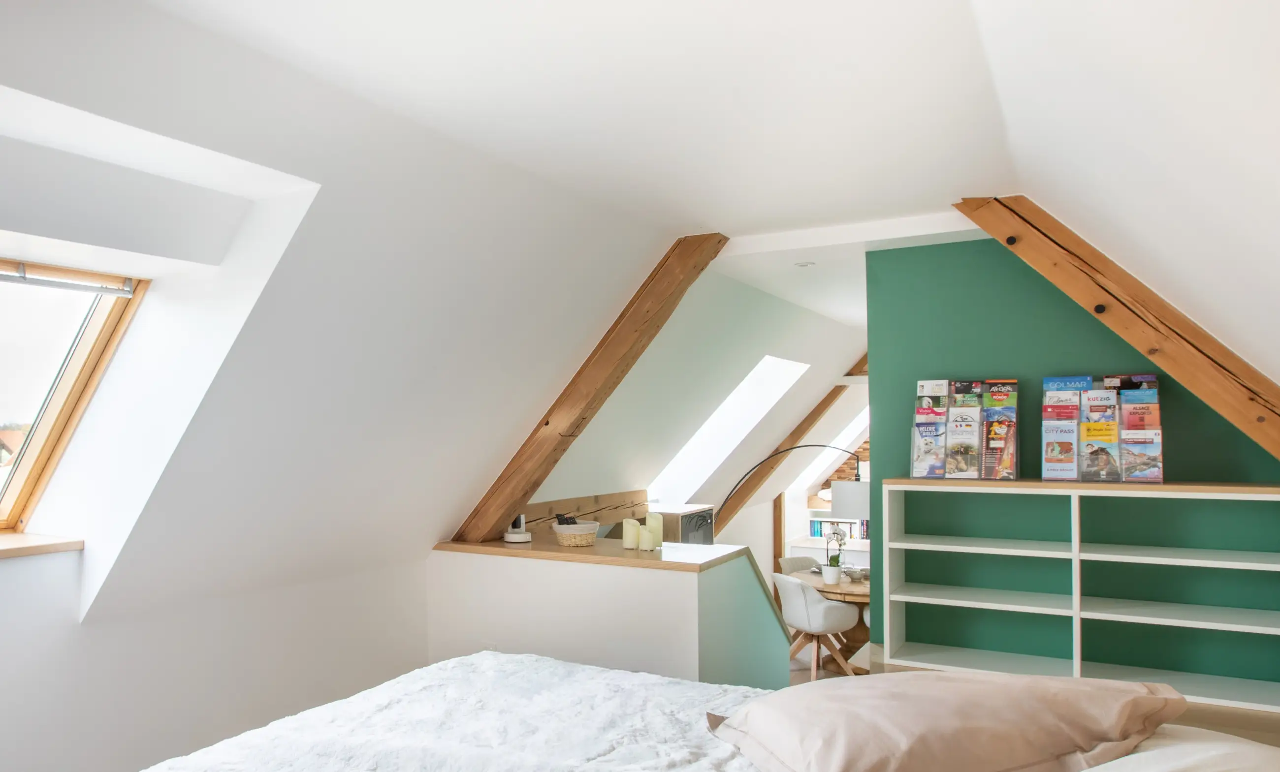 Espace nuit en mezzanine avec grande fenêtre de toit et vue ouverte sur le séjour.