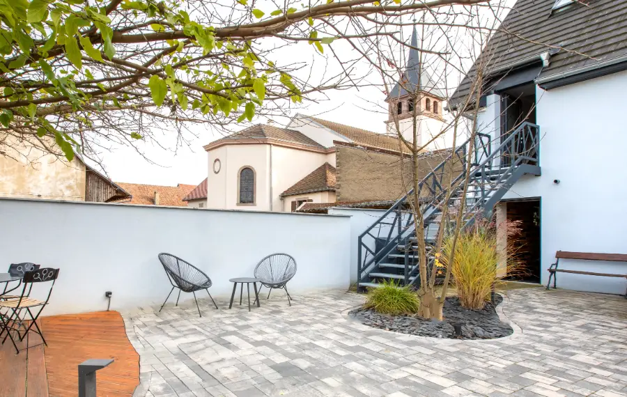 Terrasse privée du gîte Porte D avec coin détente et chaises design sur un espace extérieur ouvert.